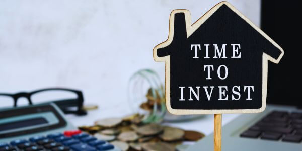 House shaped sign with "Time to Invest" written on